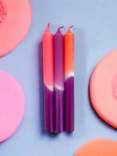 three candles sitting next to each other on top of pink and orange soaps,