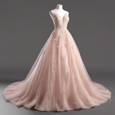 a pink wedding dress on display in front of a gray background with an empty mannequin