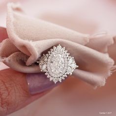 a close up of a person's hand holding an engagement ring