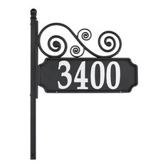 a black and white sign that says 3400 with swirls on the top, next to a light pole