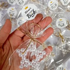 a person holding a bag filled with small white pearls and gold ribbon on top of it