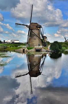 a windmill is reflected in the still water