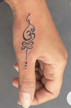 a woman's hand with a tattoo design on the thumb and wrist, which has an omen symbol tattooed on it