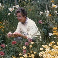 a woman kneeling down in a field of flowers