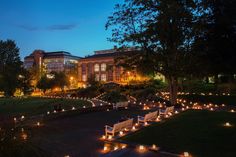 several park benches are lit up with candles in front of a building and trees at night