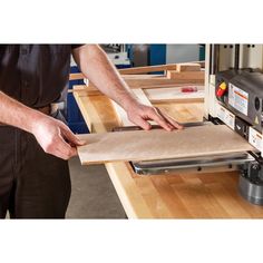 a man is using a table saw to cut plywood planks on a workbench