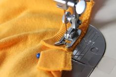 the sewing machine is working on the yellow sweater