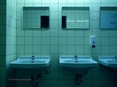 three sinks in a public restroom with mirrors on the wall and soap dispenser above them