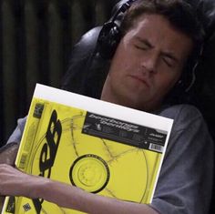 a man with headphones is holding a cd in his hands and looking at it