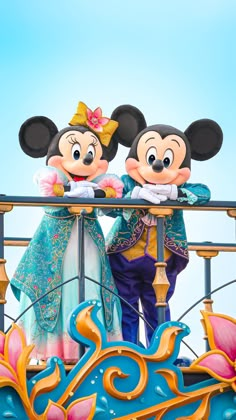 two mickey and minnie mouse characters standing on top of a roller coaster at disney world