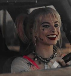 a woman sitting in the driver's seat of a car with makeup on her face