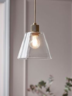 a clear glass light hanging from a ceiling fixture in a room with pink walls and flowers