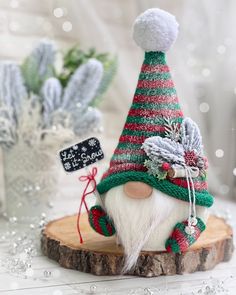 a gnome figurine sitting on top of a piece of wood next to some plants