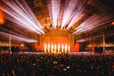 a large group of people in front of a stage with bright lights on the ceiling