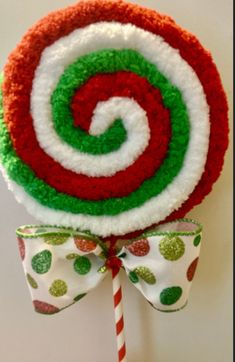 a candy lollipop is decorated with green, red and white circles on it