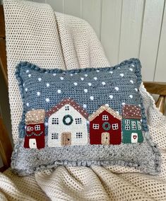 a pillow with houses on it sitting on a chair in front of a white wall