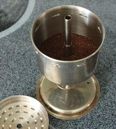 a coffee grinder is on the floor next to a strainer with ground in it