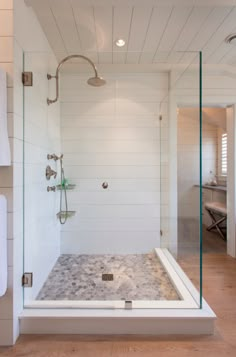 a walk in shower sitting next to a white towel on a rack and wooden floor