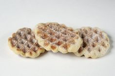 three waffles on a white surface with powdered sugar