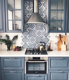 a kitchen with blue cabinets and tile backsplashes on the counter top, next to a stove