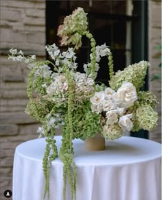 two vases filled with flowers sitting on top of a white tablecloth covered table