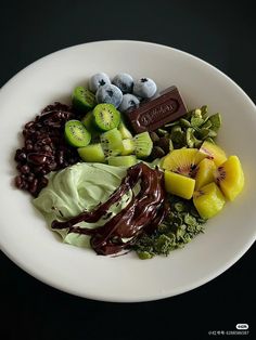 a white plate topped with different types of fruit and veggies next to chocolate