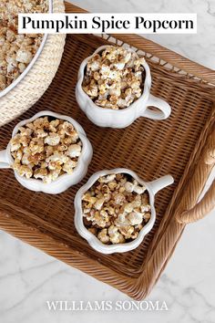 three white bowls filled with popcorn sitting on top of a wicker tray