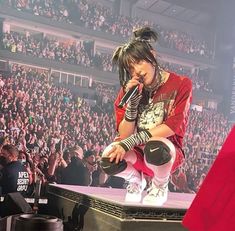 a woman sitting on top of a stage in front of a crowd