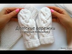 two hands are holding white knitted mittens