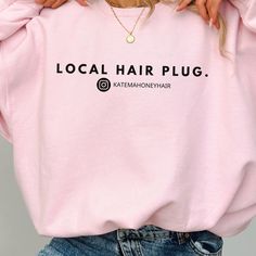 a woman wearing a pink sweatshirt with the words local hair plug on it's chest