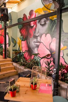 the interior of a restaurant with colorful murals on the wall and wooden tables in front of them