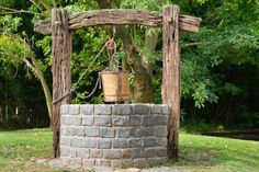 an outdoor fire pit with a potted plant on it and a wooden arbor in the background