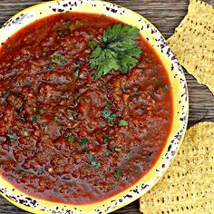 a bowl filled with chili and tortilla chips on top of a wooden table