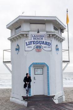 a man standing in front of a lifeguard tower on the beach