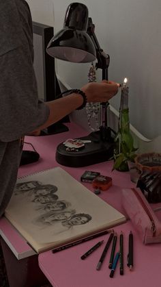 a person is lighting a candle on a pink table