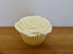 a white frosted cupcake sitting on top of a wooden table