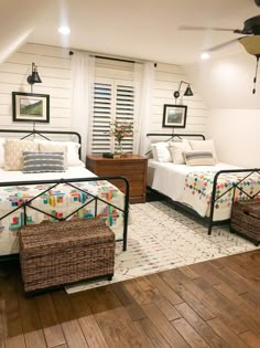 two beds in a room with white walls and wooden floors, one has a basket on the floor