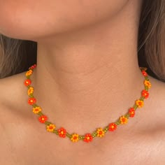 a woman wearing an orange and yellow necklace with flowers on the bottom of her neck