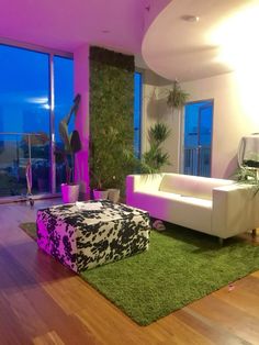 a living room filled with furniture and a large window covered in purple light next to a green rug