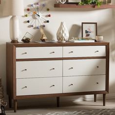 a white and brown dresser sitting next to a wall with pictures on top of it