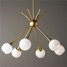 a brass chandelier with five white glass balls hanging from it's center