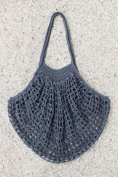 a gray crocheted bag sitting on top of a white floor next to a pair of scissors