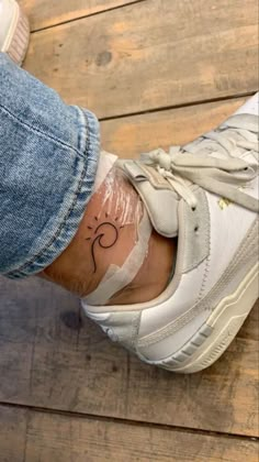 a person's foot with a small tattoo on their left leg and the bottom part of her shoe covered in plastic