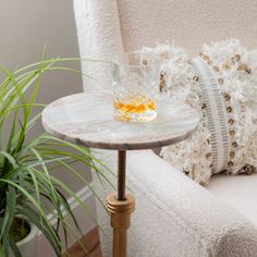 a small table with a glass on it next to a couch and potted plant