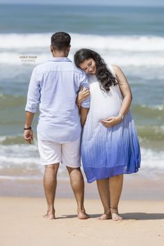 a pregnant couple walking on the beach together