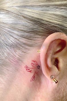 a close up of a person with a tattoo on their left side of the ear