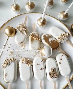 a white plate topped with cake pops covered in gold sprinkles