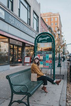 a woman sitting on top of a green bench