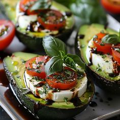 avocado stuffed with tomatoes, mozzarella and basil on a plate next to other vegetables