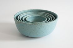 a stack of blue ceramic bowls stacked on top of each other in front of a white background